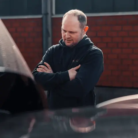 Florian Bornholdt mit verschränkten Armen vor einem Backsteingebäude auf dem Hof